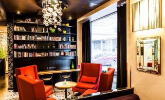 a cozy coffee shop with red chairs and a black bookshelf filled with books , creating a comfortable atmosphere for customers at Park Inn by Radisson Central Tallinn