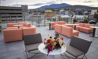 a rooftop patio with several chairs and tables , as well as a vase of flowers at Crowne Plaza Hobart, an IHG Hotel