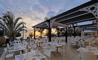 an outdoor dining area at a restaurant , with tables and chairs set up for guests to enjoy a meal at Roca Nivaria Gran Hotel