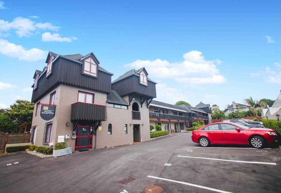 a red car is parked in front of a building with a black roof and many windows at Knights Inn