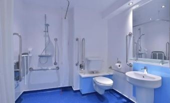 a bathroom with a toilet , sink , and mirror , as well as a shower with grab bars at Travelodge Nottingham Trowell M1