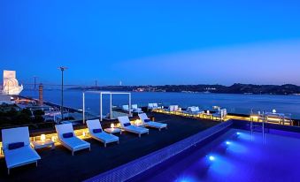 a rooftop pool overlooking the city skyline , with several lounge chairs placed around the pool for relaxation at Altis Belem Hotel & Spa, a Member of Design Hotels