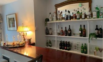 a well - stocked bar with various bottles and glasses , along with a wooden counter and a lamp at Lydgate House Hotel