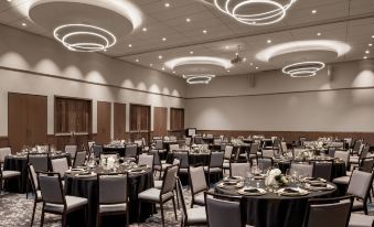 a large conference room with multiple round tables and chairs , all set for a formal event at Civic Hotel, Autograph Collection