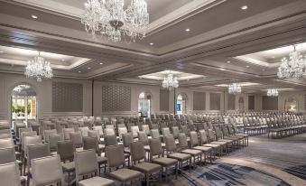 a large conference room filled with rows of chairs arranged in a symmetrical fashion , with multiple chandeliers hanging from the ceiling at The Ritz-Carlton, Laguna Niguel