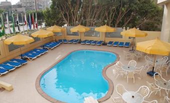 a large swimming pool surrounded by lounge chairs and umbrellas , with people enjoying their time in the pool area at Aracan Pyramids Hotel