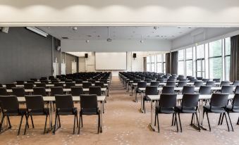 an empty conference room with rows of chairs and a projector screen at the front at Quality Hotel Entry