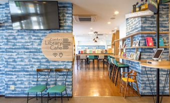 a modern cafe with blue and white decor , wooden floors , and various seating options including tables , chairs , and a bookshelf at Comfort Hotel Koriyama