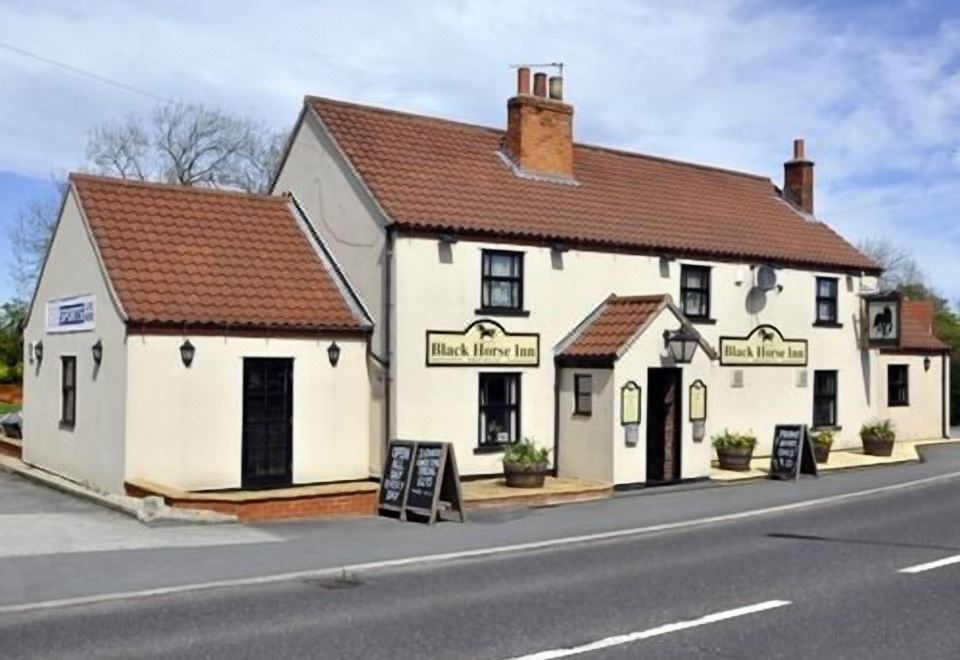 "a white building with a red roof and the words "" black monkey inn "" written on it" at The Black Horse Inn