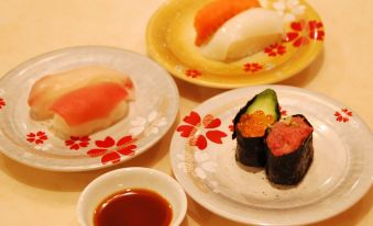 a dining table with a variety of sushi dishes , including tuna , salmon , and rice , accompanied by chopsticks at Fuji Matsuzono Hotel