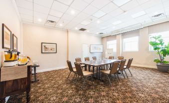 a conference room with a round table surrounded by chairs , and a framed picture hanging on the wall at Hotel Santa Barbara