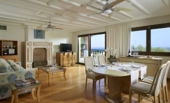a spacious living room with a dining table , chairs , and a television in the background at Aldemar Knossos Royal