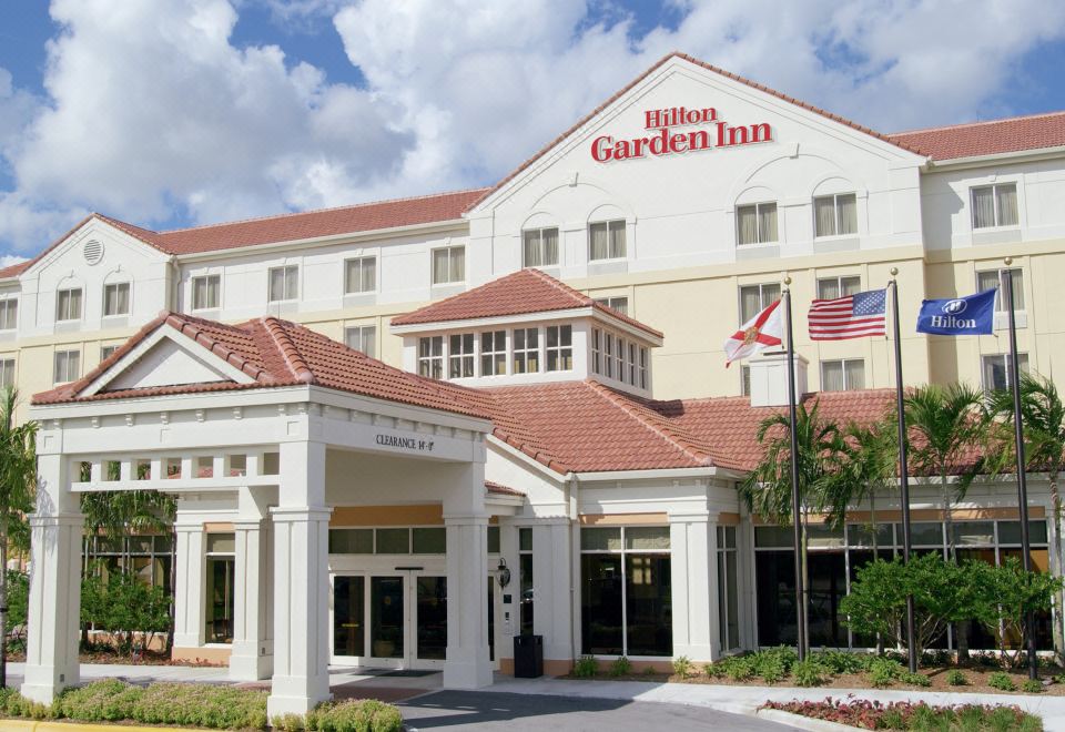 "a large white building with the words "" hilton garden inn "" on it , surrounded by trees and bushes" at Hilton Garden Inn Gilroy
