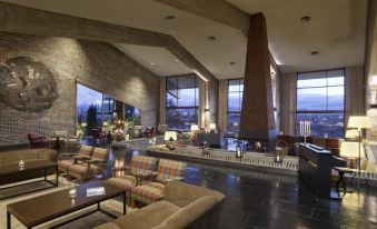 a large hotel lobby with a fireplace , multiple couches , and chairs arranged in a seating area at Parador de Santo Estevo