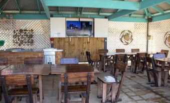 a dining area with wooden tables and chairs , a television mounted on the wall , and a covered area with a grill at Seaspray Beach Holiday Park