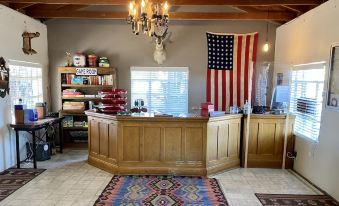 a large wooden reception desk in a room with a rug , an american flag , and various decorative items at Antelope Lodge