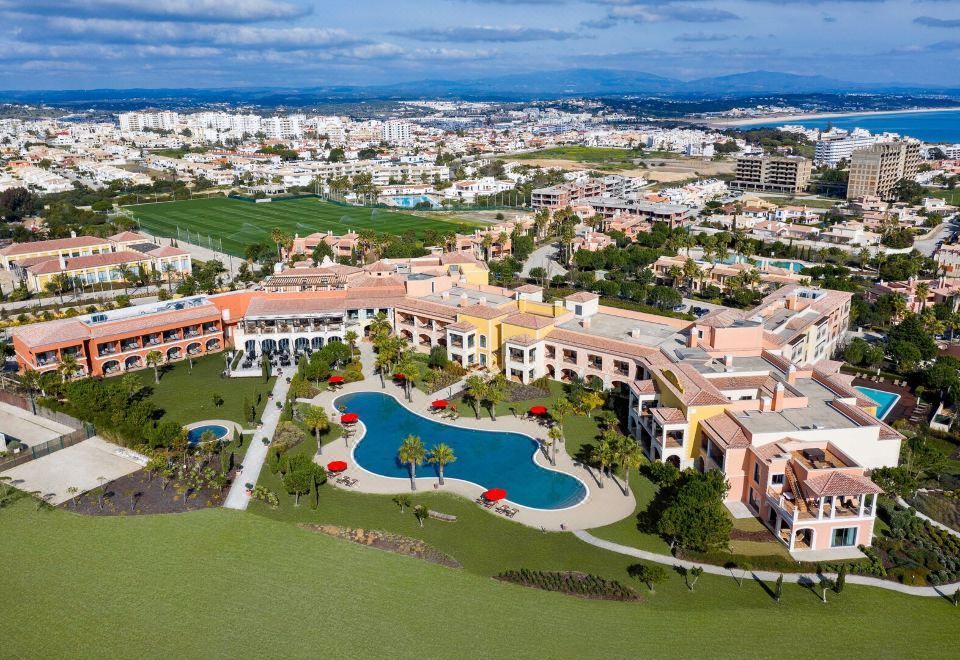 aerial view of a large resort complex with multiple buildings and a swimming pool surrounded by green fields at Cascade Wellness Resort