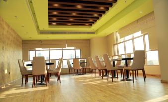 a large , empty conference room with rows of chairs and tables , wooden flooring , and large windows at Royal View Hotel