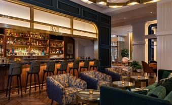 a modern bar with various seating options , including couches and chairs , as well as a dining table at Canopy by Hilton Philadelphia Center City
