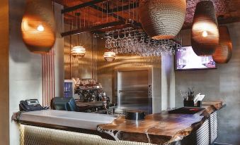 a bar with a wooden counter , pendant lights , and a television mounted on the wall at Hotel the Public - Special Category