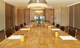a long wooden dining table with chairs arranged around it , ready for a group of people to sit and eat at Island Escape by Burasari