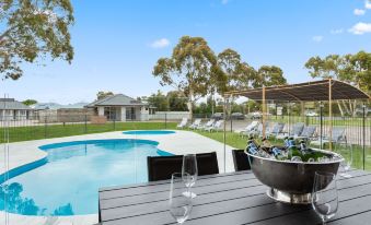 a backyard with a pool surrounded by patio furniture , including a dining table and chairs at Sanctuary Inn on Westernport
