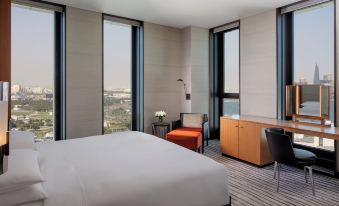 a modern hotel room with a large window offering a view of the city , a bed , and a desk at Park Hyatt Doha