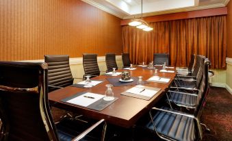 a conference room with a long wooden table , black chairs , and multiple paper items on the table at Holiday Inn Long Island - Islip Arpt East