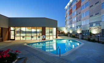 a large swimming pool is surrounded by a modern building with glass windows and doors at Four Points by Sheraton Saginaw