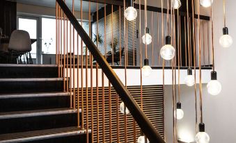 a staircase with a wooden railing and string lights hanging from the ceiling , creating a cozy atmosphere at Hotel-B