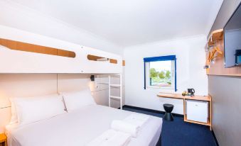 a hotel room with two beds , one on top of the other , and a bathroom in the background at ibis budget Casula Liverpool
