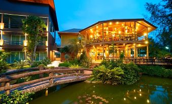 a wooden house with a large deck and pond , surrounded by greenery , at dusk at Blues River Resort