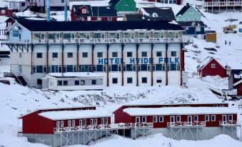 a snow - covered city with a large hotel building , possibly a hotel or resort , surrounded by snow - covered mountains at Hotel Hvide Falk