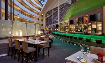 a restaurant with a bar and dining area , where people are seated and enjoying their meals at Lindner Hotel Leverkusen Bayarena