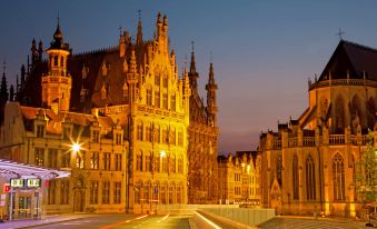 a beautiful nighttime view of the grand place in the city of brussels , belgium , with its illuminated buildings and lights reflecting in the water at Novotel Leuven Centrum