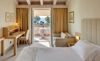 a hotel room with a bed , couch , dining table , and sliding glass door leading to a balcony at Hotel Caesius Thermae & Spa Resort