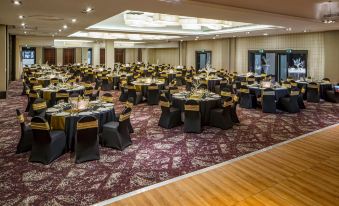 a large banquet hall filled with numerous tables and chairs , ready for a formal event at Crowne Plaza Stratford Upon Avon