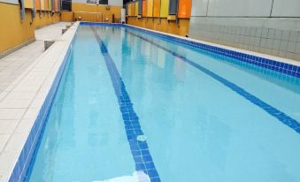 a long , empty swimming pool with blue tiles and yellow borders is surrounded by a yellow wall at Arrow on Swanston