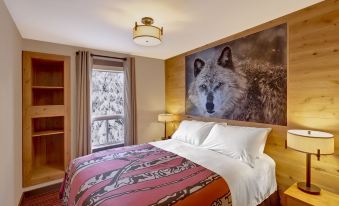 a cozy bedroom with a large bed and a wolf mural on the wall , creating a warm and inviting atmosphere at Banff Rocky Mountain Resort