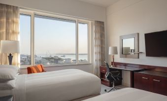 a hotel room with two beds , a desk , and a large window overlooking the city at Guyana Marriott Hotel Georgetown