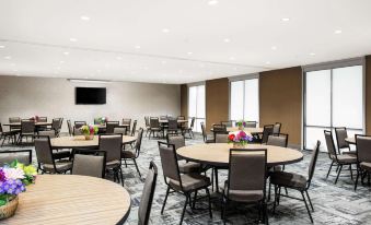 a large dining room with multiple tables and chairs arranged for a group of people to enjoy a meal together at Home2 Suites by Hilton Long Island Brookhaven