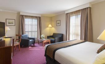 a hotel room with a bed , two chairs , a table , and a window with curtains at Hotel Grand Chancellor Launceston
