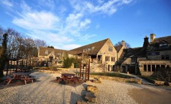 a large stone building with a courtyard , surrounded by a gravel area and a wooden bench at The Frogmill Hotel