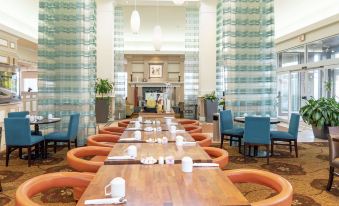 a large dining room with wooden tables and chairs arranged for a group of people to enjoy a meal at Hilton Garden Inn Wooster