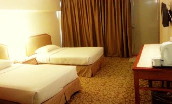 a hotel room with two beds , one on the left and one on the right side of the room at Shahzan Inn Fraser's Hill