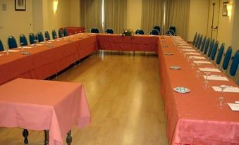 a large conference room with multiple long tables set up for a meeting , each table having its own set of red tablecloths at La Canada