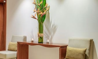 a modern office space with white walls , wooden furniture , and a large flower arrangement on the desk at The Manor - New Delhi