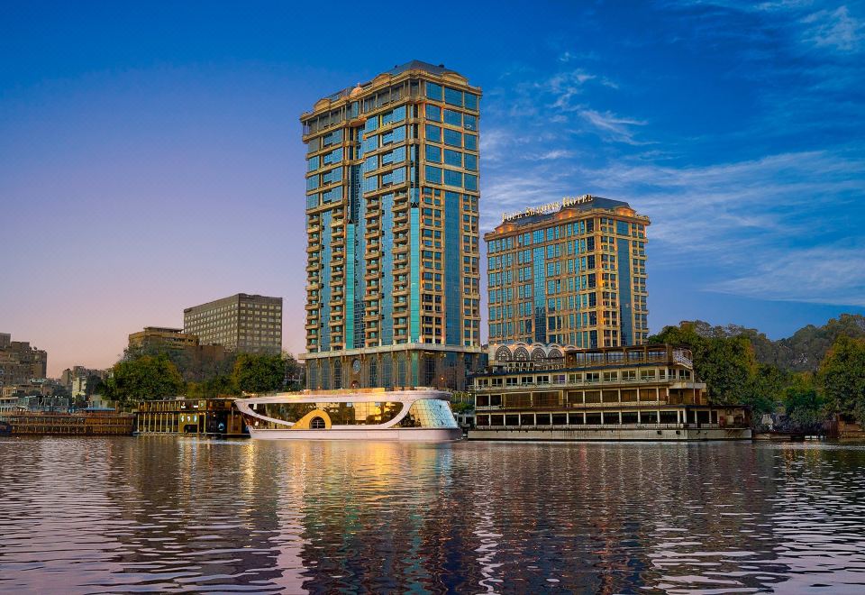 a large building with a modern design is situated on the shore of a lake at Four Seasons Hotel Cairo at the First Residence