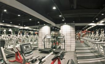 a large gym with various exercise equipment , including treadmills and stationary bikes , under a white ceiling at Incheon Airport Hotel