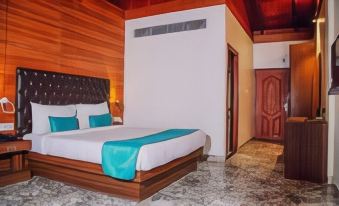 a hotel room with a wooden floor , a bed with blue sheets , and a door leading to another room at Holiday Inn Beach Resort